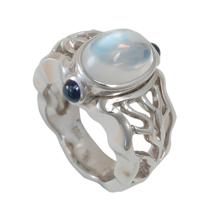 16077 Open Flowing Lines Moonstone and Sapphire Ring Designed & Handmade by Kaufmann de Suisse in 18kt White Gold featuring one Cabochon Cut Moonstone weighing 3.36cts, flanked by two Round Caboch